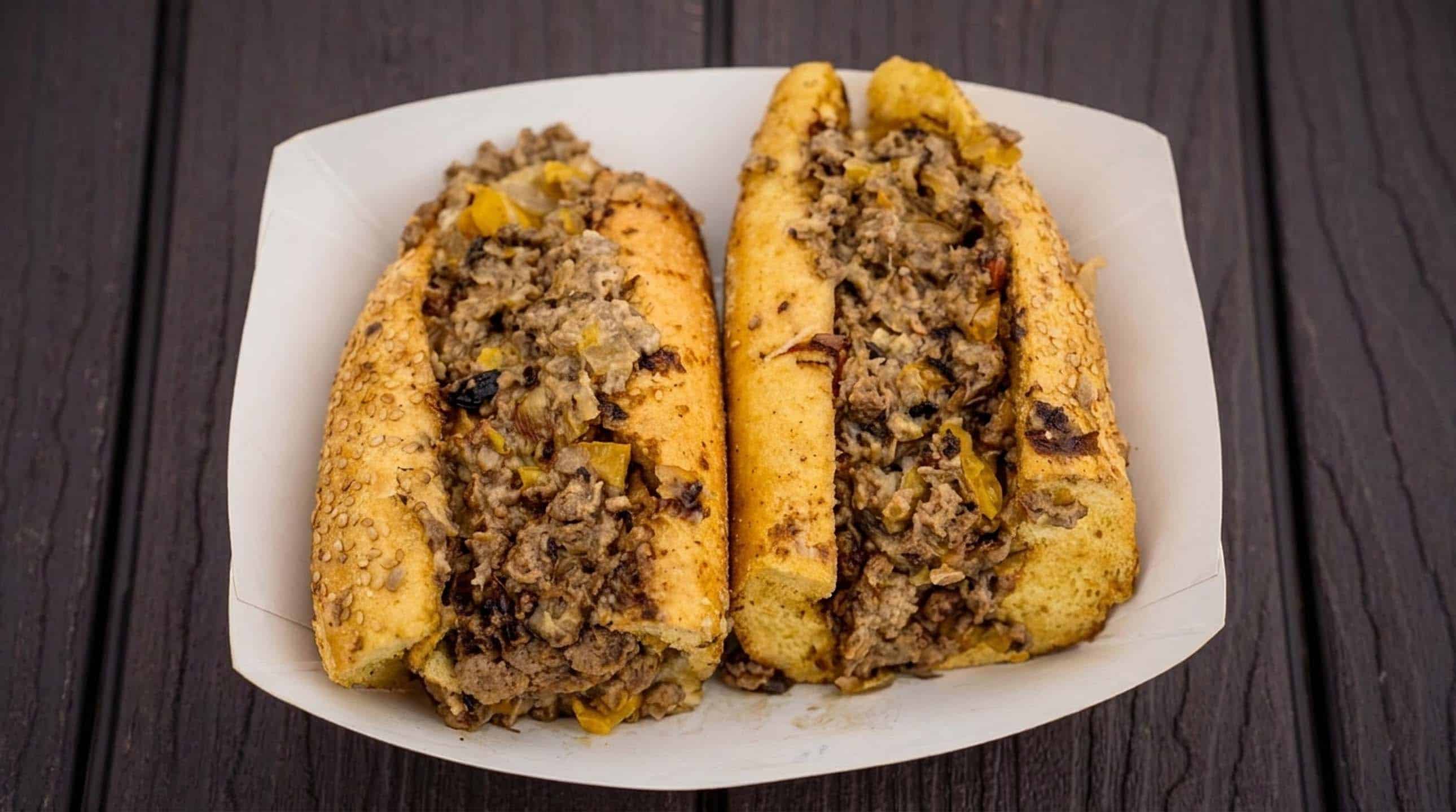A ribeye cheesesteak cut in half and piled high in a paper boat